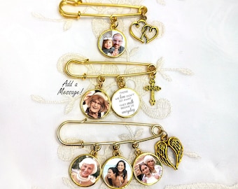 May include: Gold-toned safety pins with photo pendants and charms. The pendants feature family photos and text that reads "THOSE WE LOVE DON'T GO AWAY THEY WALK BESIDE US everyday." Charms include a cross, heart, and angel wings.