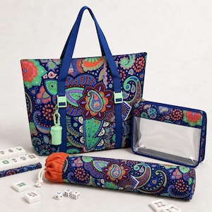 May include: A tote bag, a rectangular clear-front pouch, and a cylindrical drawstring case, all featuring a dark blue fabric with a vibrant multicolored paisley pattern. The tote has blue straps and a small light green accessory attached.
