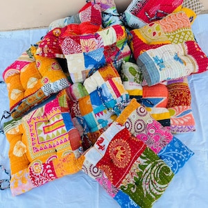 May include: A collection of colorful, patchwork cushions. The cushions feature a variety of patterns and colors, including red, yellow, blue, and green. Each cushion is square or rectangular and appears to be made from repurposed fabric.