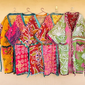 May include: Five quilted robes hanging on hangers, each featuring distinct vibrant patterns and colors including yellow, pink, red, and green with intricate stitching details, V-necklines, wide sleeves, and matching fabric waist ties.
