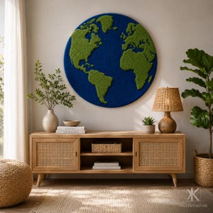 May include: A circular wall art piece featuring a world map with textured green landmasses against a deep blue ocean background. The continents are depicted in a raised, moss-like material, creating a tactile representation of the globe.