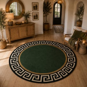 May include: A round green rug with a Greek key border in black and white, and a gold accent. The rug is on a wooden floor in a well-lit room with a mirror and furniture.