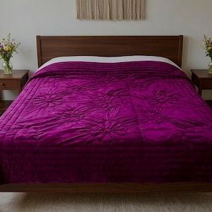 Peut inclure: Un lit avec un cadre et une tête de lit en bois foncé, recouvert d'une couette magenta vif. La couette présente un motif floral matelassé et des lignes horizontales. Deux petites tables de chevet en bois avec des fleurs encadrent le lit.