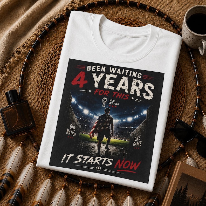 May include: White t-shirt with a graphic design. The design features the text "Been Waiting 4 Years For This" with a soccer player and stadium illustration. The text "It Starts Now" is also included. The shirt is a crew neck style.