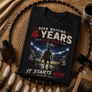 May include: Black t-shirt with the text "Been Waiting 4 Years For This". The shirt features a graphic of a person on a soccer field with a flag, and the words "One Nation, One Game, It Starts Now".