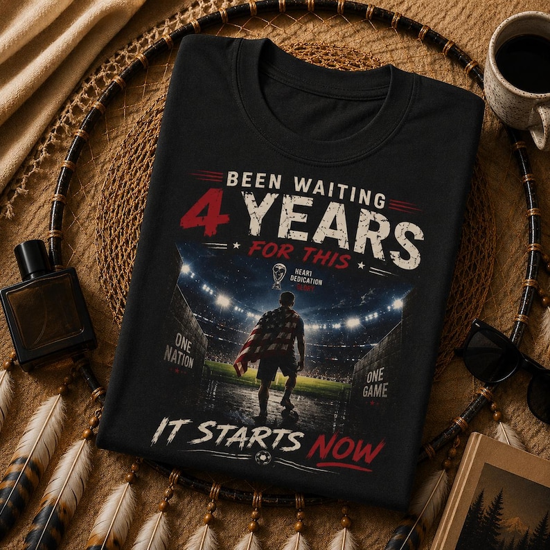 May include: Black t-shirt with a soccer stadium graphic. The shirt features the text "Been Waiting 4 Years For This" in white and red, with "It Starts Now" in red. A soccer ball graphic is at the bottom.