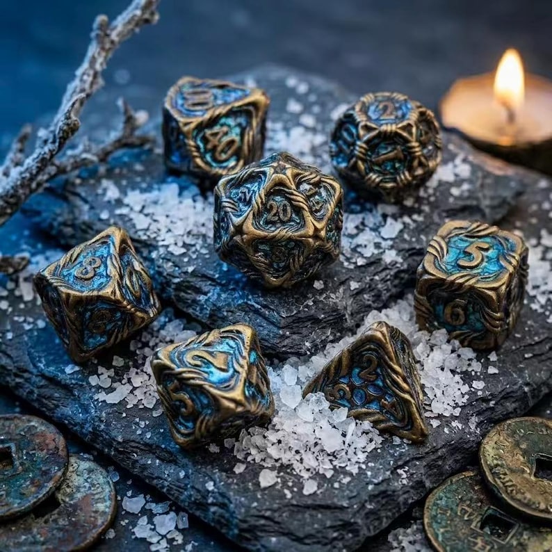 May include: A collection of antique-style dice with bronze and blue accents. The dice are arranged on a dark, textured surface with scattered white crystals and antique coins. A lit candle and a branch are in the background.