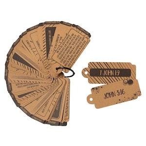 May include: A set of tan rectangular paper cards with rounded edges, held together by a black metal ring. Each card features dark brown printed text, including Bible verses like 1 John 1:9 and John 3:16, alongside decorative striped patterns.
