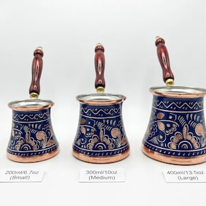 Puede incluir: Tres cafeteras turcas de cobre y azul con asas de madera. Las ollas están decoradas con motivos florales y están etiquetadas como pequeñas (200 ml), medianas (300 ml) y grandes (400 ml).