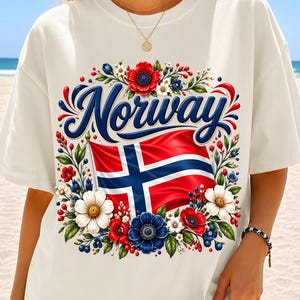 May include: An off-white short-sleeve t-shirt featuring the word Norway in blue script above a graphic of the Norwegian flag. The flag is surrounded by a colorful floral wreath composed of red, white, and blue flowers and green leaves.
