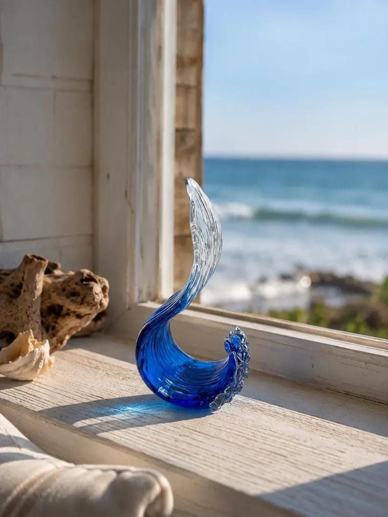 Puede incluir: Una escultura de vidrio con forma de ola oce&aacute;nica rompiendo, que presenta una base azul profundo que transiciona hacia una cresta transparente y texturizada. La pieza tiene una forma curva y fluida con detalles intrincados en los bordes.
