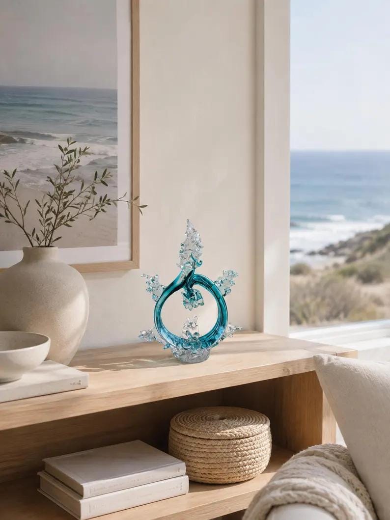 Puede incluir: Una escultura decorativa de cristal con un anillo circular central de color azul cerceta y protuberancias transparentes, dentadas y cristalinas que se extienden hacia arriba y los lados, sobre una base de cristal transparente texturizado.