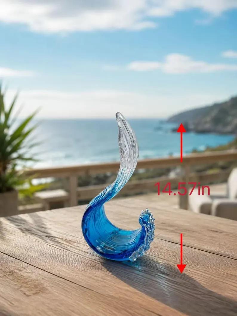 Puede incluir: Una escultura de vidrio transparente y azul con forma de ola rompiendo. La pieza presenta un degradado de azul intenso en la base que se vuelve transparente hacia la parte superior. Una flecha roja indica una altura total de 37 cm.