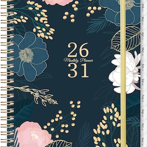 May include: A dark blue monthly planner with a spiral binding and a gold elastic closure. The cover features a floral pattern with pink, white, and dark blue flowers, green leaves, and gold accents. The text 26 31 Monthly Planner is centered.