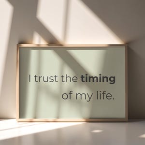 Könnte beinhalten: Gerahmter Druck mit dem Text "I trust the timing of my life". Der Text ist in Dunkelgrau auf hellgrünem Hintergrund. Der Rahmen hat eine helle Holzfarbe.