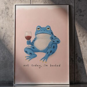 May include: Framed art print showing a blue frog with a glass of red wine, with the text "not today, I'm booked". The frog has a bored expression. The background is a light pink colour.