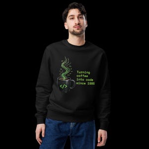 Peut inclure: Un sweat-shirt noir à manches longues avec un motif représentant une tasse de café, un symbole de code vert et de la vapeur formée de caractères numériques. Le texte Turning coffee into code since 1995 est imprimé en vert sur le devant.