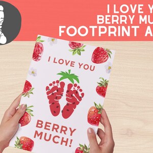 Könnte beinhalten: Eine weiße Karte mit roten Erdbeeren und grünen Blättern bedruckt. Die Karte sagt "Ich liebe dich sehr!" mit zwei roten Fußabdrücken in der Mitte.
