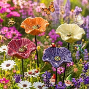 Peut inclure: Quatre tuteurs de jardin en céramique en forme de fleurs orange, jaune, rouge et violette, chacun doté d'un centre en cristaux verts, agrémenté de petites figurines d'abeilles, de coccinelles et de nains, parmi des fleurs de jardin variées.