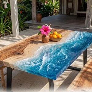 Peut inclure: Une table à manger rectangulaire présentant une surface en bois naturel d'un côté et une incrustation en résine bleue imitant les vagues de l'océan avec de l'écume blanche de l'autre. La table repose sur des pieds en métal noir et deux bancs.