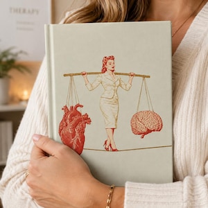 Puede incluir: Un libro de tapa dura en color verde salvia claro con una ilustración central de una persona con traje haciendo equilibrio sobre una cuerda floja. Sostiene una vara con un corazón anatómico rojo a un lado y un cerebro humano rojo al otro.