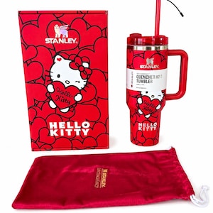 May include: A red Stanley Quencher H2.0 tumbler featuring a Hello Kitty graphic and heart pattern, accompanied by its matching red box with the same design and a red velvet drawstring pouch with the Stanley logo printed in gold on the front.