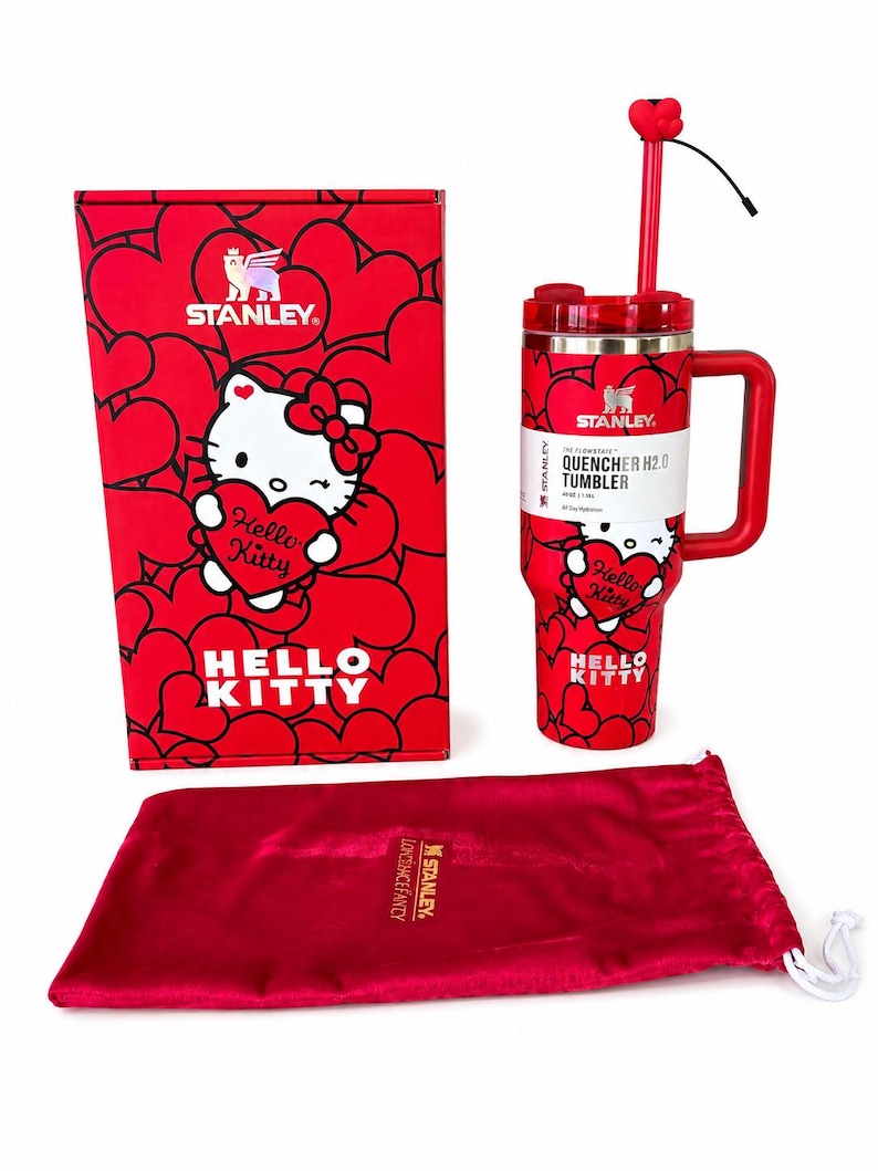 May include: A red Stanley Quencher H2.0 tumbler featuring a Hello Kitty graphic and heart pattern, accompanied by its matching red box with the same design and a red velvet drawstring pouch with the Stanley logo printed in gold on the front.