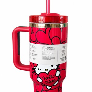 May include: A red stainless steel tumbler featuring a repeating black heart pattern and a Hello Kitty graphic holding a heart. It includes a red handle, a clear lid with a red straw, and a white product label detailing the FlowState 3-position lid.