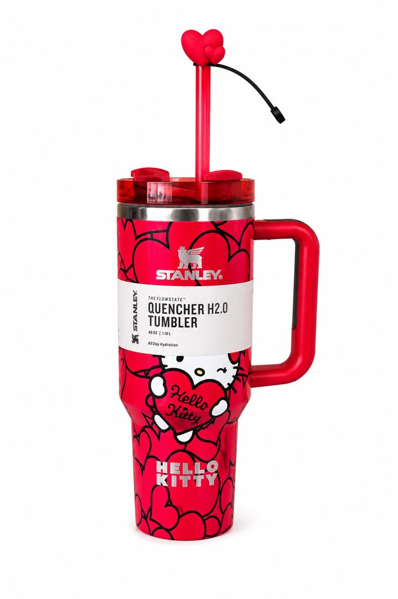 May include: A red Stanley Quencher H2.0 tumbler with a 40 oz capacity, featuring a Hello Kitty graphic, a heart-patterned exterior, a red handle, a clear lid, and a red straw topped with a heart-shaped accessory. The label displays the text Stanley.