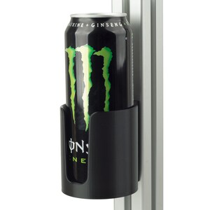 Peut inclure: Un porte-canette en plastique noir fixé sur un profilé vertical en aluminium argenté. Le support contient une canette de boisson énergisante noire avec un logo griffe vert vif et le texte TAURINE + GINSENG imprimé sur le bord supérieur.