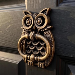 Può includere: Un battente per porta in metallo color bronzo a forma di gufo, caratterizzato da un design piumato dettagliato e grandi occhi circolari. Il gufo tiene tra gli artigli un anello ovale liscio, che funge da meccanismo di battuta.