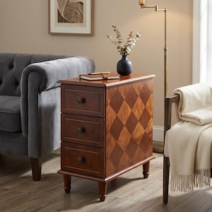 May include: A dark brown wooden side table with three drawers and a diamond pattern on the side. The table has a small, black vase with greenery on top. The drawers have round, dark knobs.