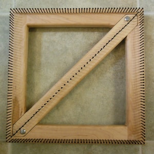 May include: A square wooden loom with a diagonal support beam. The loom has rows of nails along the edges and is made of light wood.