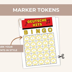 May include: A printed bingo game sheet titled "DEUTSCHE HITS BINGO" with yellow circles and musical notes. The text "MARKER TOKENS" is at the top, and "MARK YOUR MOMENTS IN STYLE" is at the bottom. A paperclip and scissors are also visible.