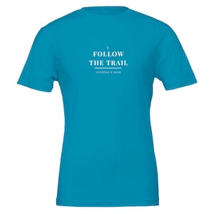 May include: A bright turquoise short-sleeve t-shirt featuring white text centred on the chest that reads I FOLLOW THE TRAIL with the smaller text certified & tired underneath, separated by a thin horizontal line.