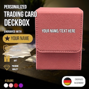 Könnte beinhalten: Eine korallenrosa, texturierte Sammelkarten-Deckbox in rechteckiger Form mit Klappverschluss. Die Vorderseite der Box ist mit dem eingravierten Text YOUR NAME/TEXT HERE versehen. Die Box hat eine kreuzschraffierte Oberfläche und sichtbare Nähte.