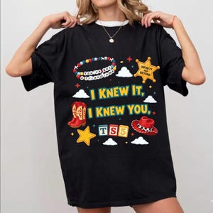 Może przedstawiać: Czarny t-shirt z kolorowym nadrukiem graficznym z tekstem "I KNEW IT, I KNEW YOU", "TS5", "You've got a friend in me" oraz "INFINITY AND BEYOND". Wz&oacute;r zawiera ilustracje czerwonych kowbojek, czerwonego kapelusza, gwiazd i chmur.