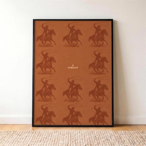 Peut inclure: Une impression d'art murale rectangulaire dans un cadre noir présentant un motif répétitif de cow-boy à cheval lançant un lasso. Le fond est d'une couleur orange terre cuite unie. Le texte A CABALLO est imprimé en blanc au centre.