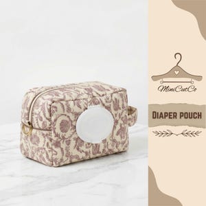 May include: A beige diaper pouch with a purple floral design. It features a white, circular opening for wipes and a small handle. The words "DIAPER POUCH" are printed on a tan background.