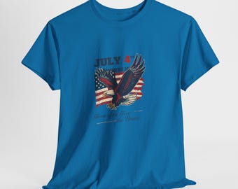May include: A blue t-shirt featuring a patriotic design. The graphic includes a bald eagle, the American flag, and the text "July 4th Independence Day" and "Home of the Free, Because of the Brave."