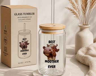 May include: A clear glass tumbler with a bamboo lid and glass straw. The tumbler features a cow graphic with the text "BEST MOOTHER EVER". The box next to the tumbler reads "GLASS TUMBLER" and "16 OZ | 473 ML".