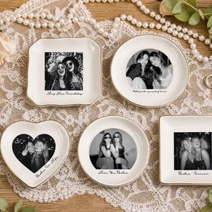 Könnte beinhalten: Fünf weiße Keramikschalen mit goldfarbenen Rändern, die schwarz-weiße Fotografien von zwei Personen und verschiedene Inschriften wie Long Live Friendship, Will you be my maid of honor, Bestie For Life, Love You Bestie und Bestie Forever zeigen.
