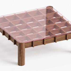 May include: A square coffee table featuring a dark brown wooden base with a grid-like structure and four cylindrical legs. The top surface is a flat, transparent, light pink acrylic sheet that rests directly on the wooden lattice frame.
