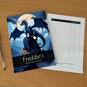 Könnte beinhalten: Ein Notizbuch mit einem blauen Drachen auf einem Felsen vor einem Vollmond. Der Einband zeigt den Text 'Freddie's Weekly School Grab List'. Daneben liegt ein weißes Blatt mit einer Tabelle zur Erfassung von Artikeln, Bedarf und aktuellem Bestand.