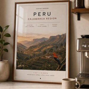 May include: A framed wall art print titled Coffee Origins Peru Cajamarca Region. The print features a landscape of mountains, a small house, and an Andean cock-of-the-rock bird. Text includes elevation 1,200-2,000 masl, variety, process, and tasting notes.