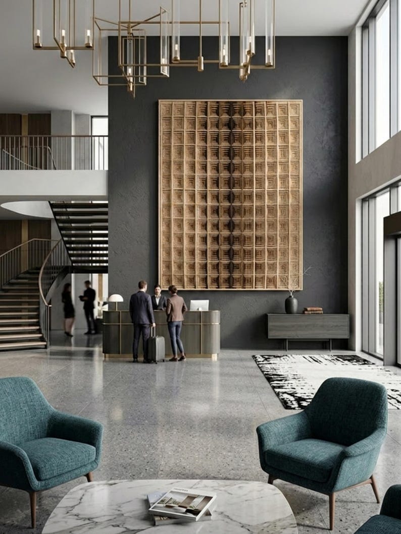 Puede incluir: Una gran pieza de arte mural cuadrada de madera clara con una cuadr&iacute;cula de paneles cuadrados empotrados cuelga de una pared gris oscuro en el vest&iacute;bulo de un hotel. El vest&iacute;bulo cuenta con sillones azul verdoso, una mesa de m&aacute;rmol y recepci&oacute;n.