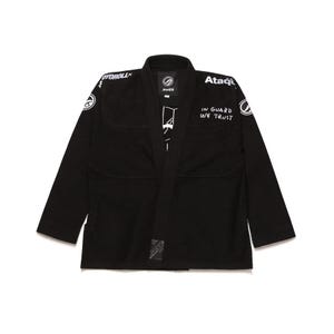 May include: Black martial arts gi with white text and logos. The gi features the text "IN GUARD WE TRUST" and the brand name "Ataqi". The gi has long sleeves and a traditional collar.