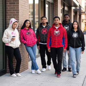 Peut inclure: Plusieurs personnes portant des sweats à capuche zippés avec des motifs de super-héros. Les sweats à capuche sont rouges, noirs et roses, avec des motifs de toiles d'araignées et d'araignées. Ils se tiennent sur un trottoir.