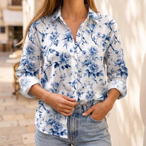 May include: White button-down shirt with a blue floral and hummingbird print. The long-sleeved shirt features a classic collar and is made of a lightweight fabric. The floral pattern includes large peony-like blooms and delicate branches.