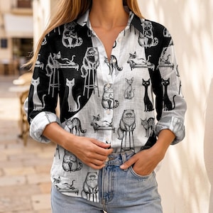 May include: A long-sleeve button-down shirt featuring a split black and white design with an all-over print of various cat illustrations. The cats are depicted in different poses, some sitting on stools or lounging on furniture, rendered in black ink.